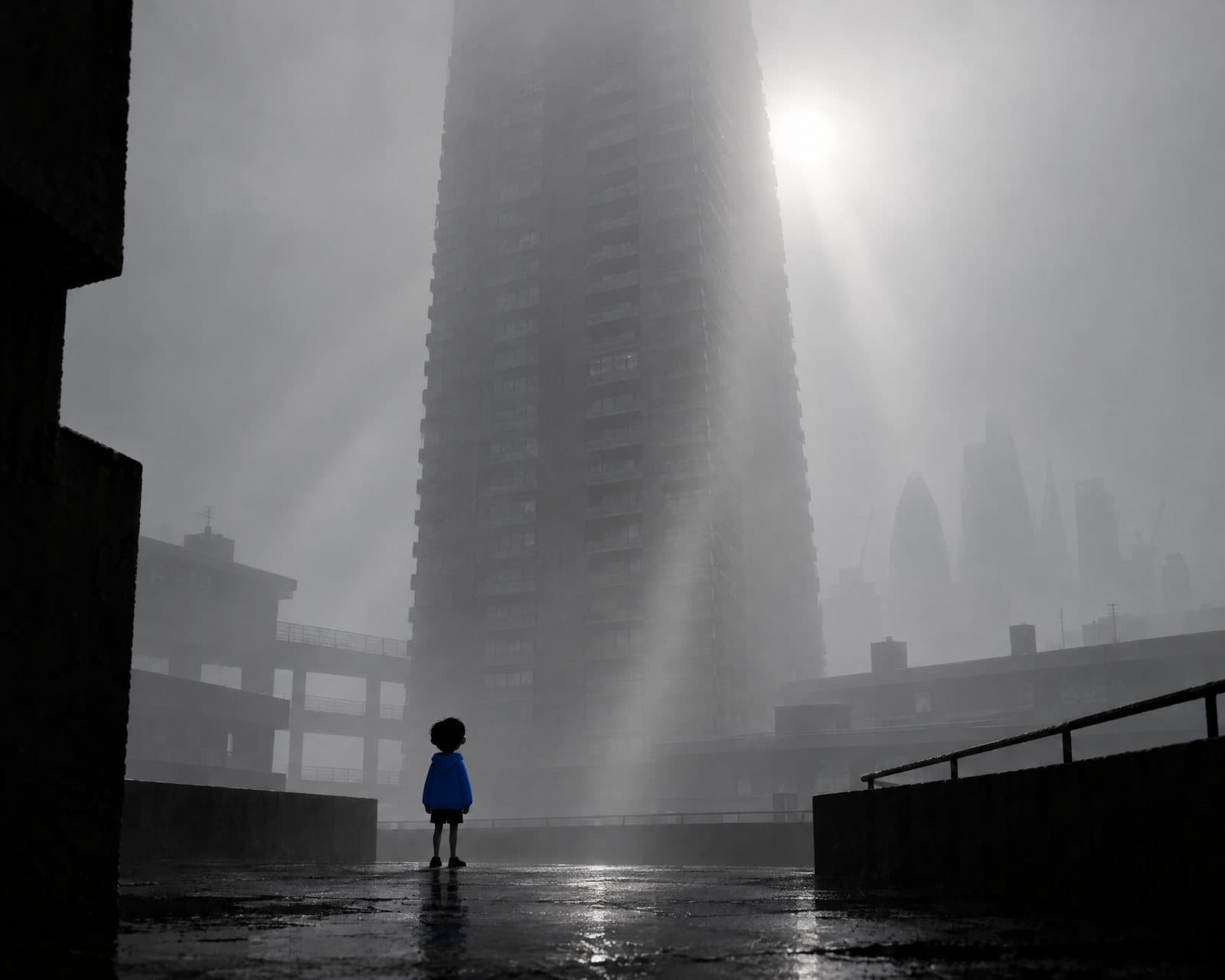 The boy in a blue hoodie on the rain-soaked podium deck, Petticoat Tower lost in the mist above him