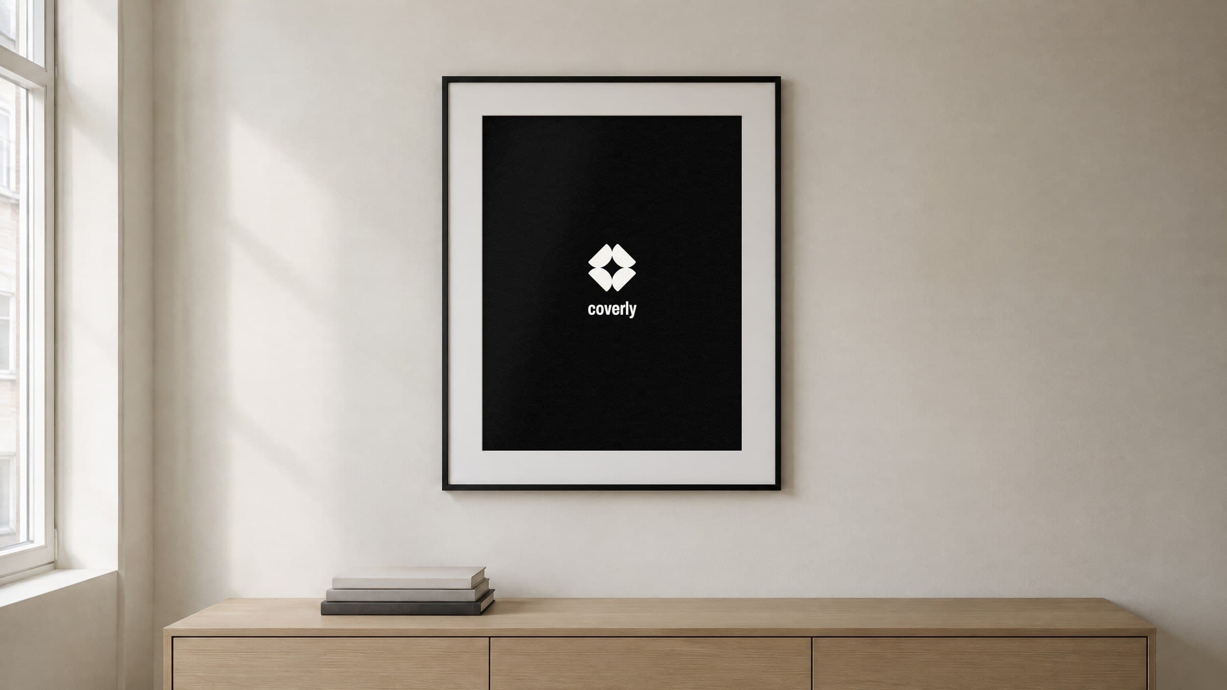 A framed black coverly poster on the wall of a design studio